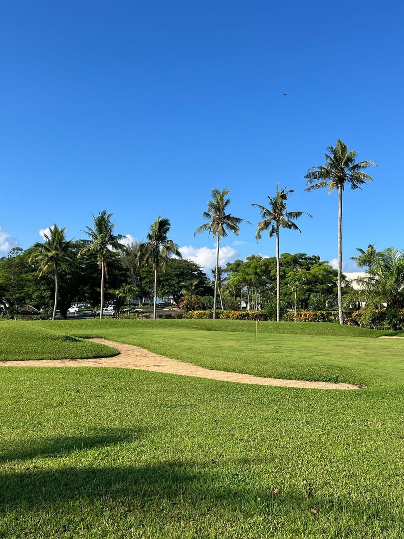 Golf course with green grass and palm trees at Warwick Le Lagon Vanuatu in Efate