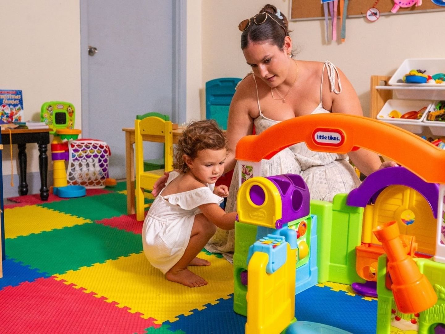 Mother and daughter playing with a colorful Little Tikes toy house in a playroom at Savannah Beach Hotel.
