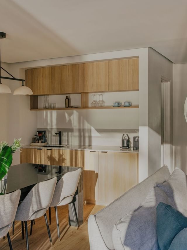 Coastal Three Bedroom Suite at Elysium Manly with a black dining table by a kitchen, featuring a round mirror