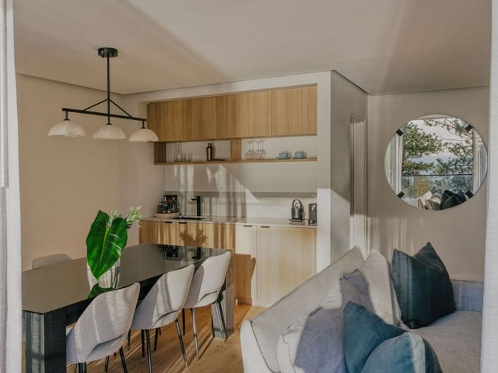 Coastal Three Bedroom Suite at Elysium Manly with a black dining table by a kitchen, featuring a round mirror