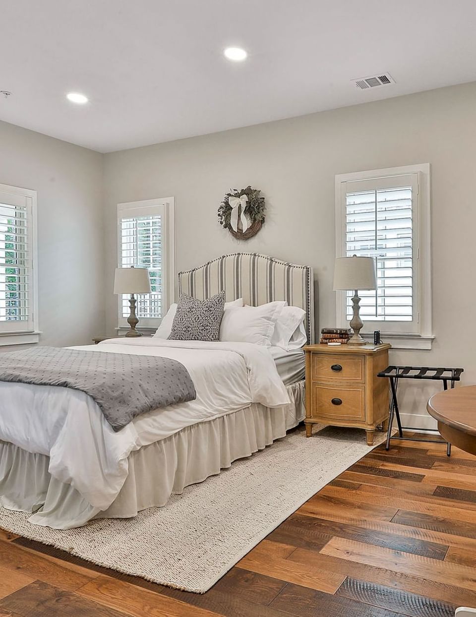 Bright Deluxe King Cottage room with taupe bedding, wooden floors, and shuttered windows by Cottages at Laurel Brooke