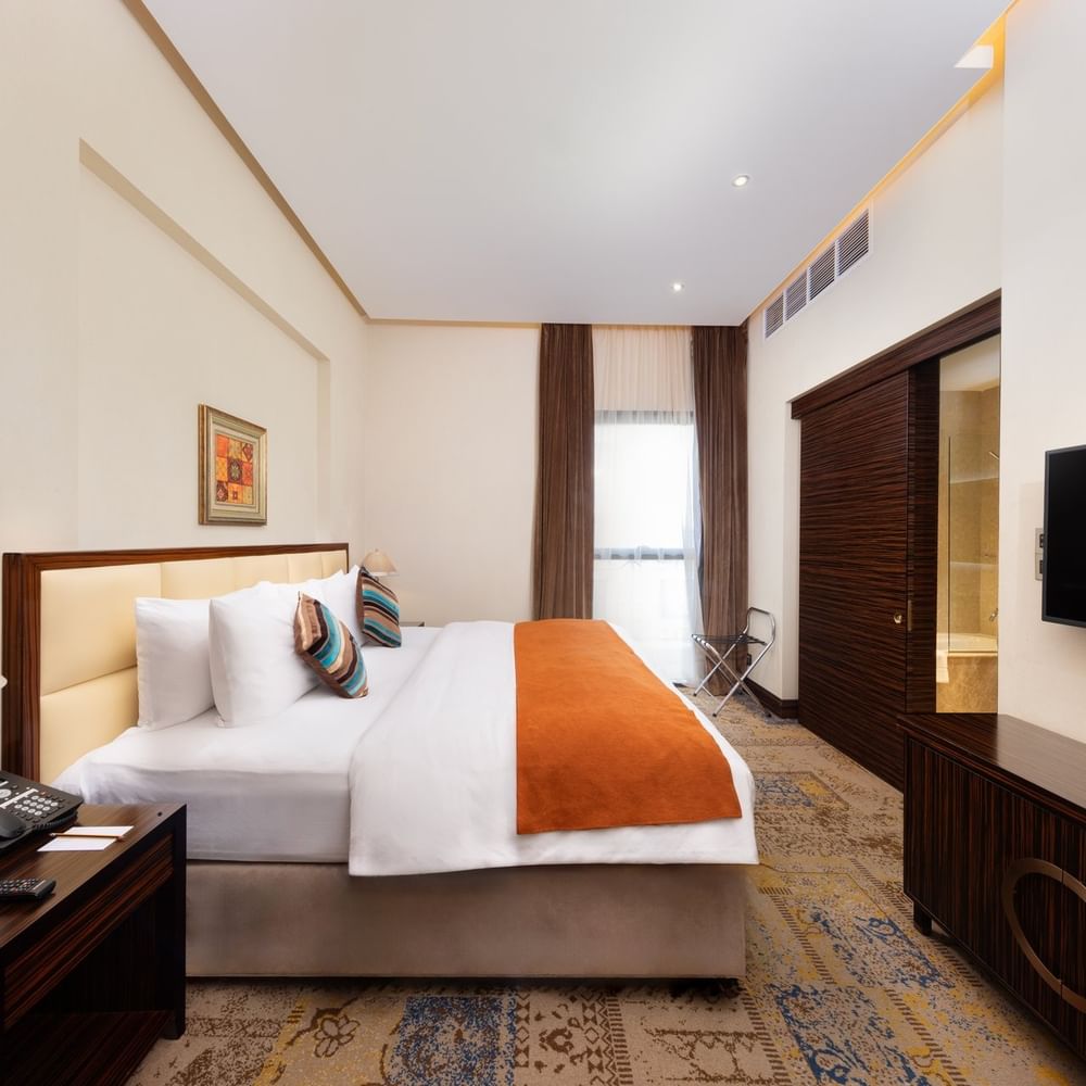 Superior King Room features a king bed with a TV under high ceilings and soft lighting at Warwick Al Khobar