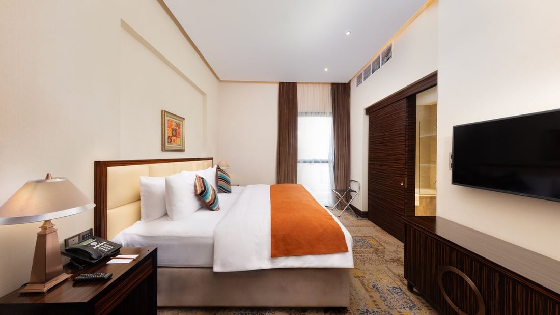 Superior King Room features a king bed with a TV under high ceilings and soft lighting at Warwick Al Khobar