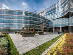Modern glass-facade medical complex with landscaped courtyard featuring planters and walkways at Koç University Hospital.