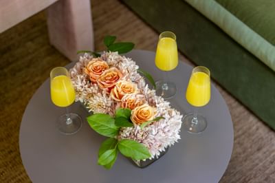 Three glasses of orange juice surround a floral centerpiece with peach roses on a round table at The Ashbrook Hotel