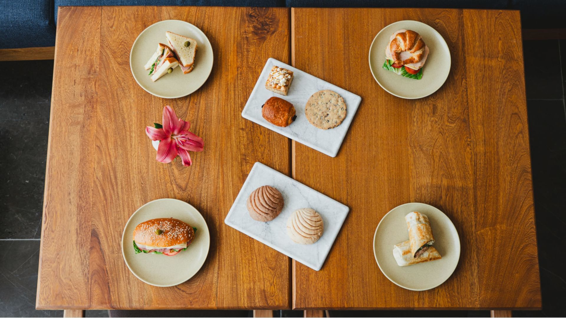 Wooden table displaying an assortment of baked goods and sandwiches on beige plates at Camino Real Zaashila Huatulco