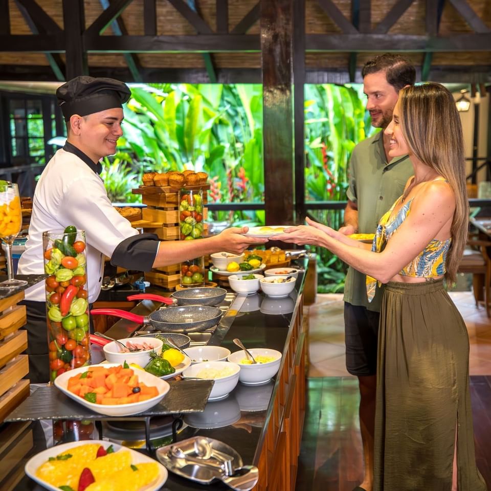 Serving food to a couple by the counter at Hideaway Rio Celeste