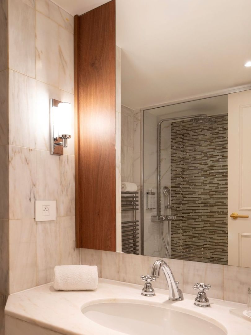 Moderne badkamer met marmeren wastafel en glazen douchecabine in een Classic Kamer bij Warwick Brussels Grand-Place