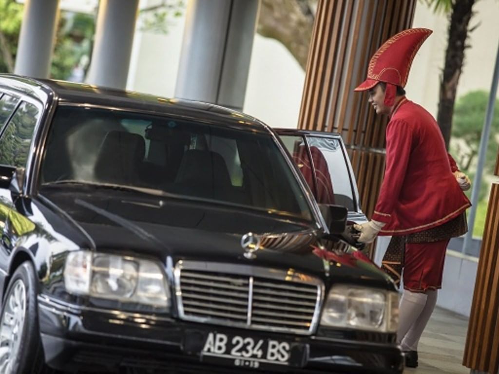 A chauffeur opening the door of a car at Royal Ambarrukmo Yogyyakarta