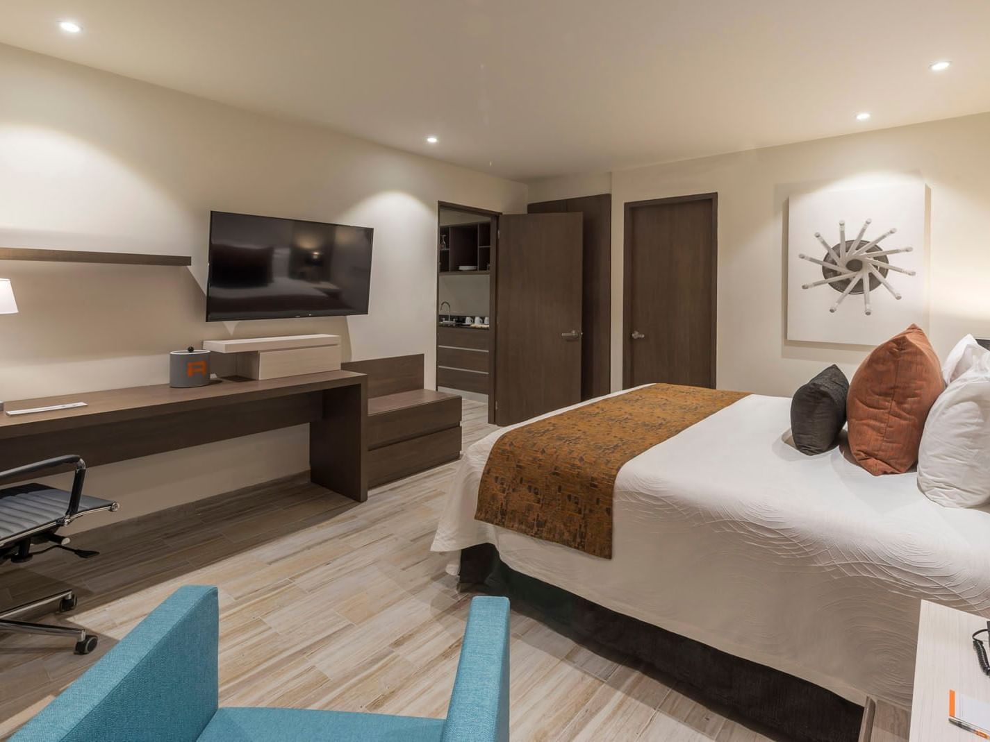 Well-appointed King Master Suite featuring a large bed, workspace, and a teal armchair in the front at Real Inn Celaya