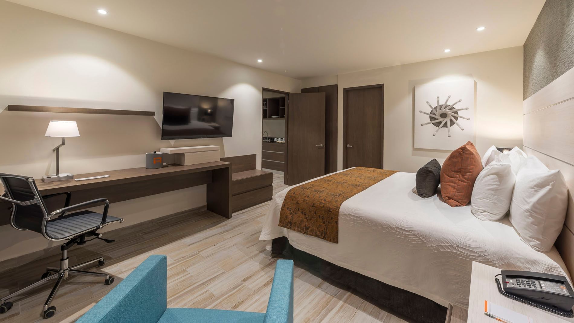 Well-appointed King Master Suite featuring a large bed, workspace, and a teal armchair in the front at Real Inn Celaya