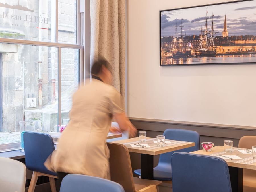 A waitress cleaning the dining table at Hotel des Marins
