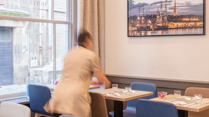 A waitress cleaning the dining table at Hotel des Marins