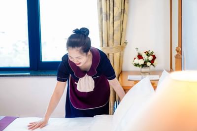 A room attendant tidying up a bed at Hanoi Daewoo Hotel