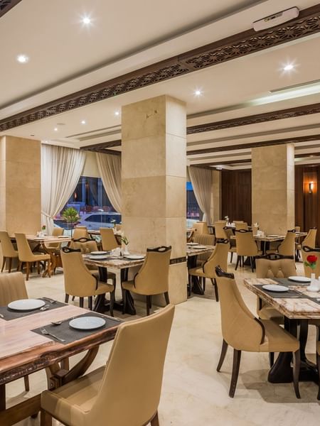 Royal Restaurant with tan chairs by marble tables under a coffered ceiling at Naviti by Warwick Al Khobar