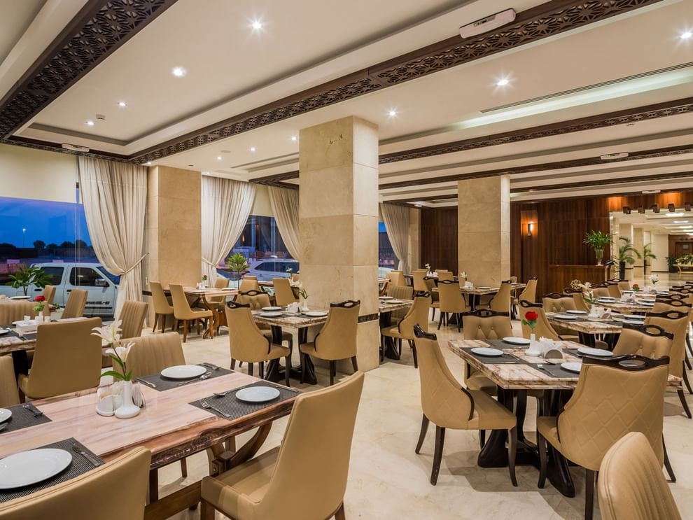 Royal Restaurant with tan chairs by marble tables under a coffered ceiling at Naviti by Warwick Al Khobar