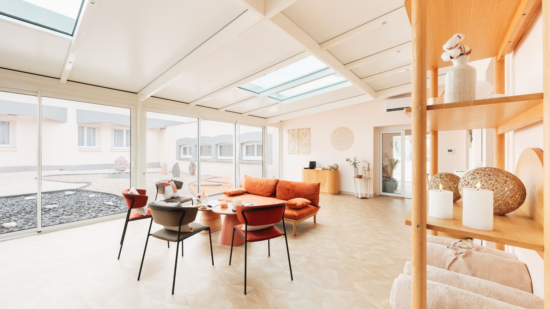 Glass sunroom lounge featuring burnt orange sofa and modern chairs around low round tables at Hôtel Causse Comtal Rodez

