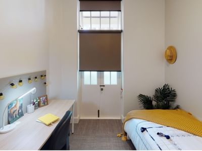 Single Room desk, bed and balcony at UniLodge Herston.