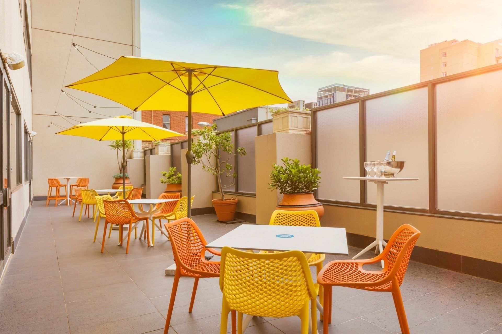 Outdoor seating area with yellow and orange chairs and tables under yellow umbrellas at Hotel Grand Chancellor Adelaide