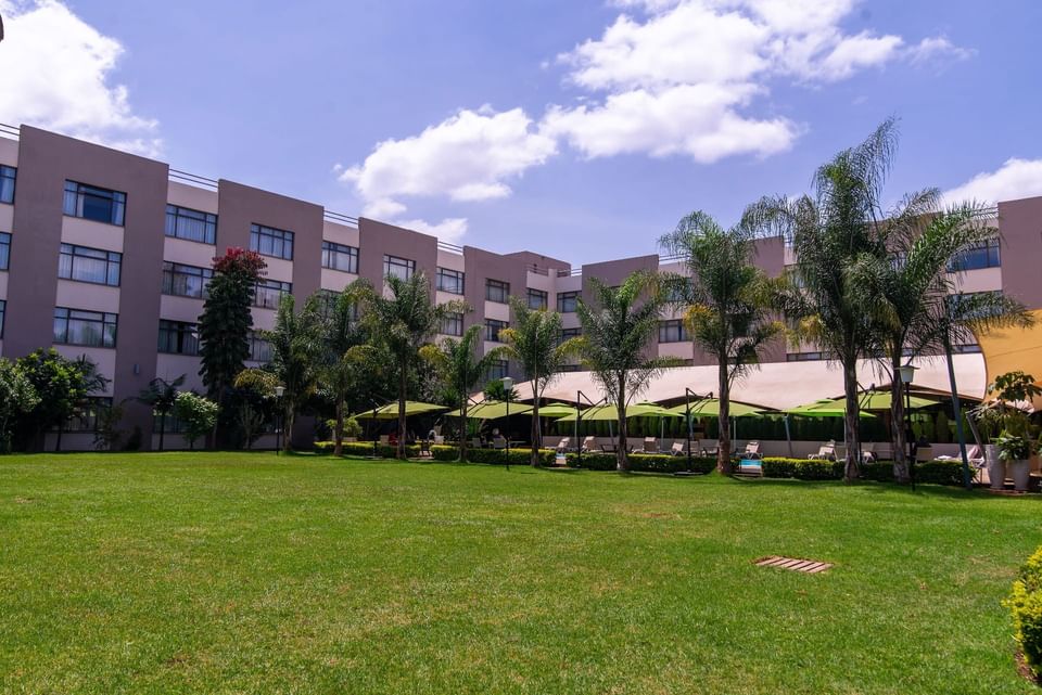 Modern hotel with green lawn and poolside umbrellas under blue sky at Tamarind Tree Hotel