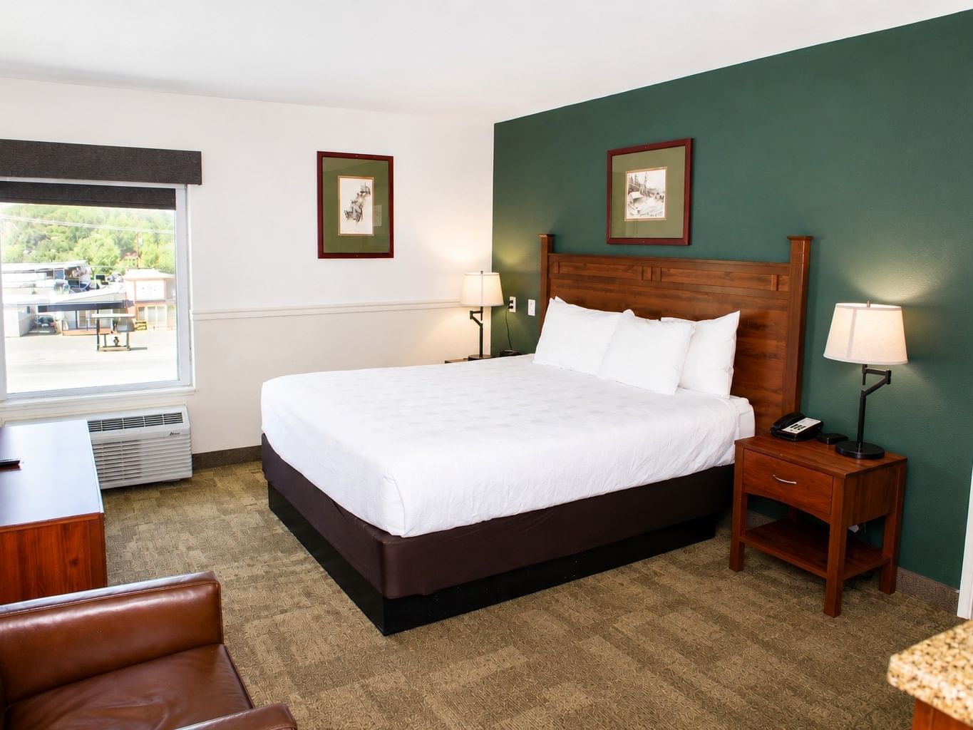 Family Suite with king bed, green accent wall, wooden furniture, and window view at - Boothill Inn