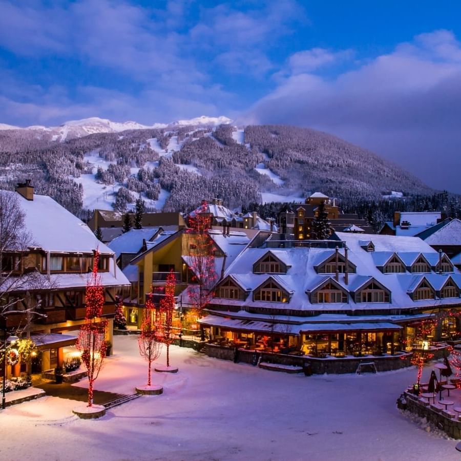 Exterior view of illuminated Blackcomb Springs Suites with mountain backdrop