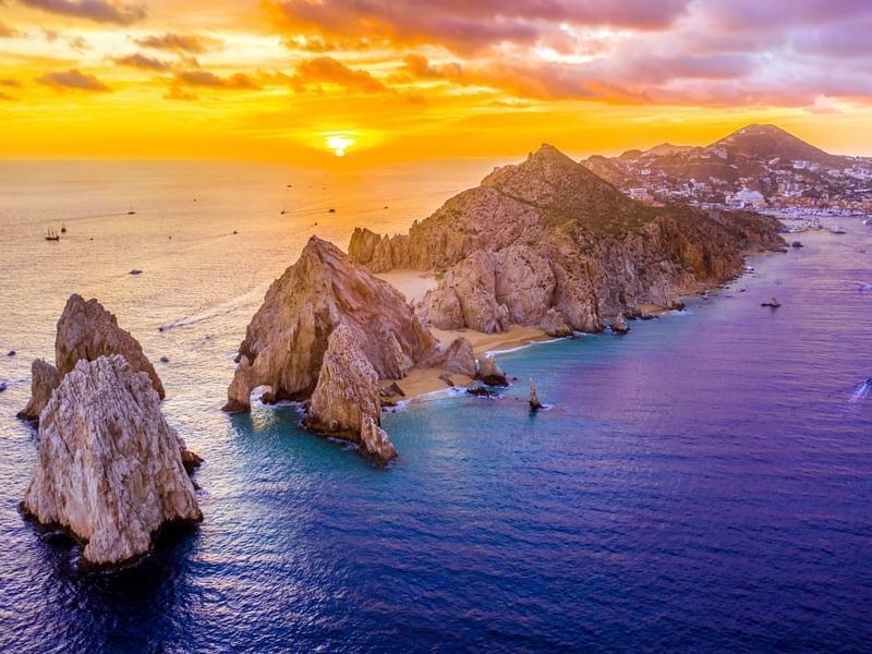 Majestic rock formations and beaches at sunset, viewed from the ocean near the Marquis Los Cabos Resort.