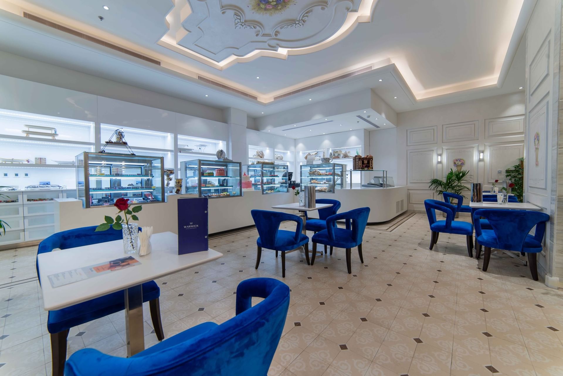 Chocolate Café featuring blue chairs by white shelving units and a chalkboard easel at Warwick Al Khobar