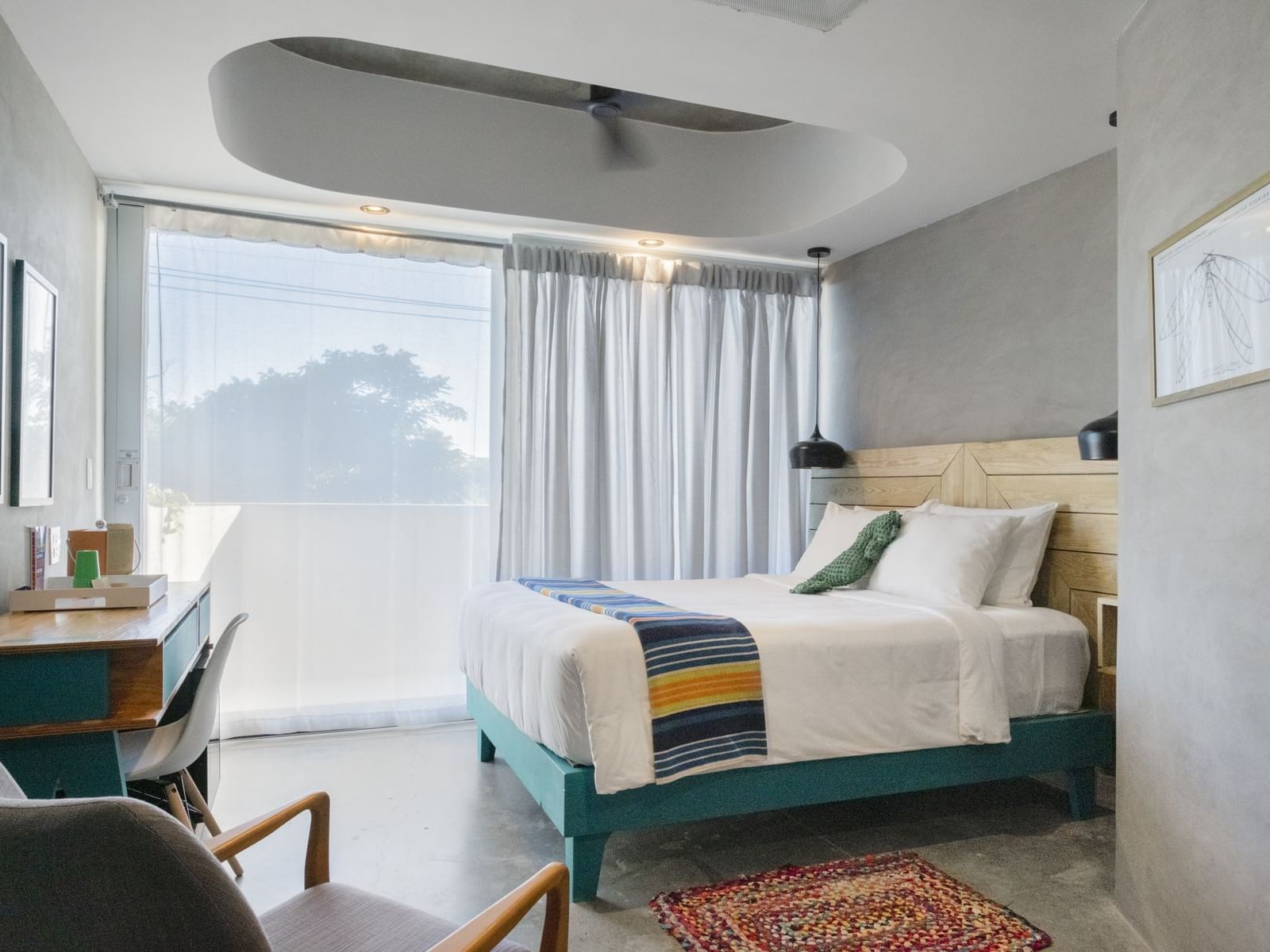 Estandar room at El Blok in Vieques with bed, desk, chair, and large window.