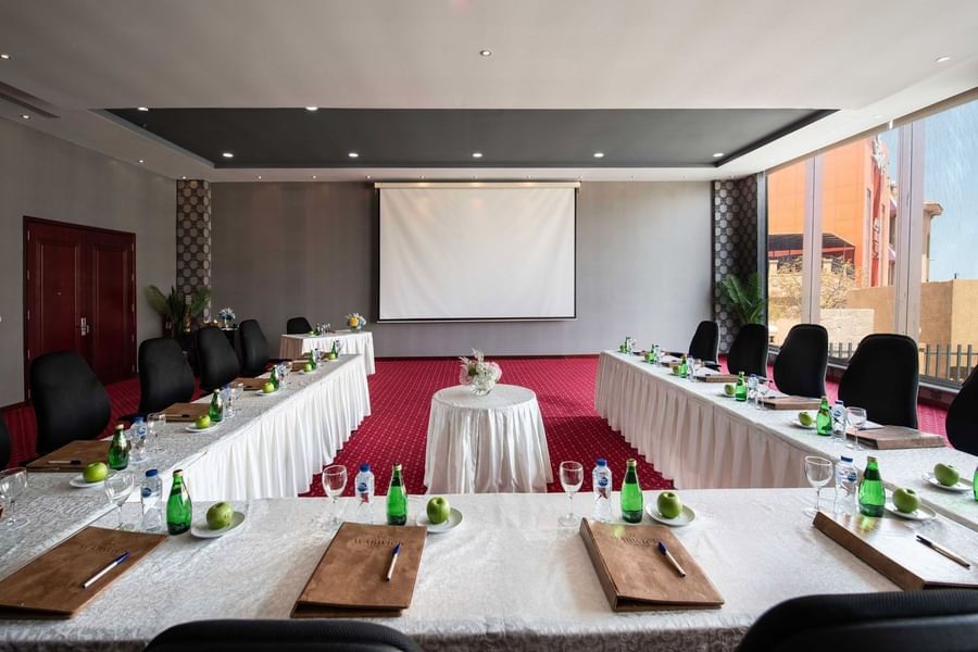 Long tables and black chairs surrounding a projector screen by a window in Crystal B at Warwick Al Jubail