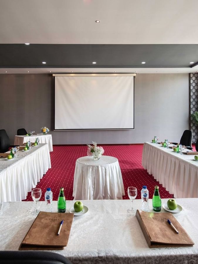 Long tables and black chairs surrounding a projector screen by a window in Crystal B at Warwick Al Jubail