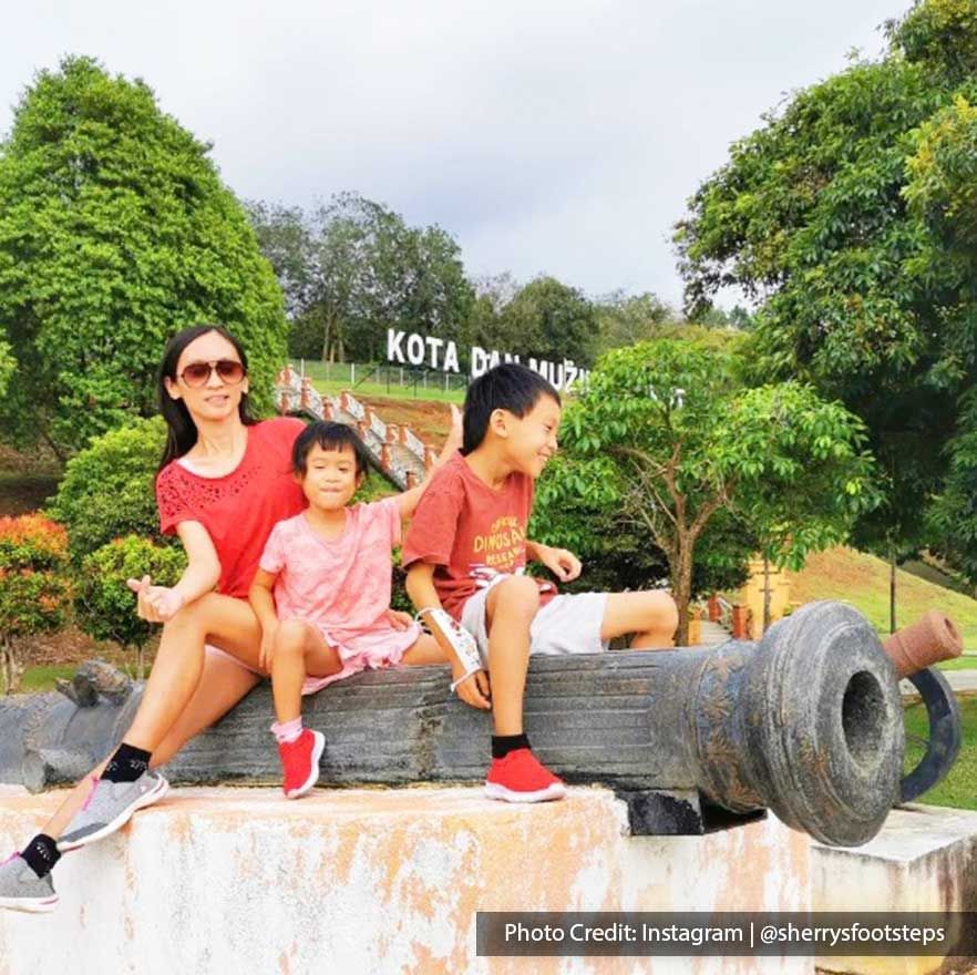 a mother and her kids sitting on a cannon at Lukut Fort and Museum