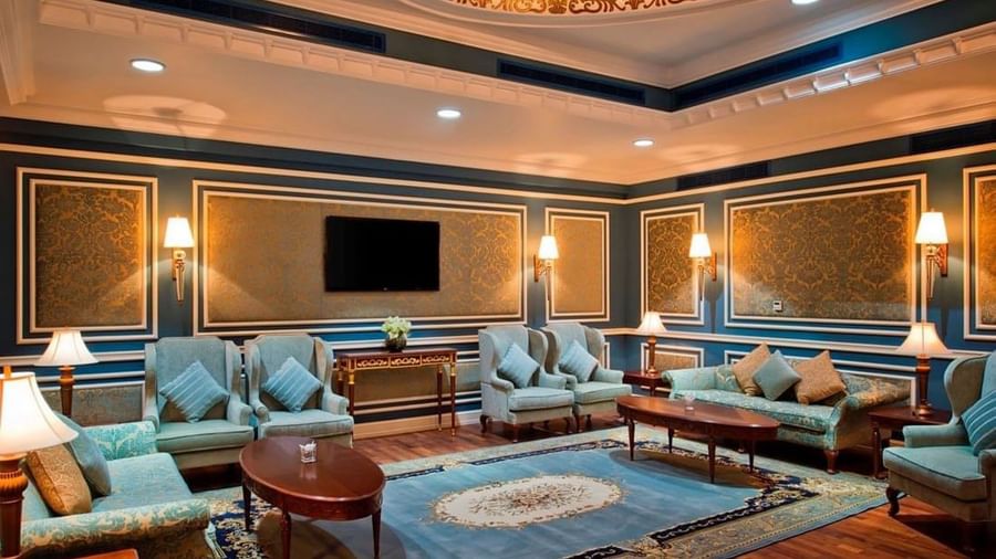 صالة فاخرة بأثاث أزرق وذهبي وجدران مزخرفة وإضاءة دافئة في Warwick Doha