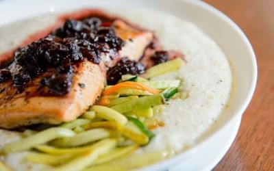 Grilled salmon fillet with rich dark berry glaze over a bed of white grits at Clemson University Conference Center & Inn