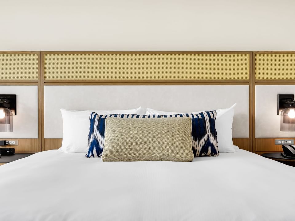 Bed with white linens, decorative pillows, and ambient lighting in La marina, ocean view king Room at El Conquistador Resort