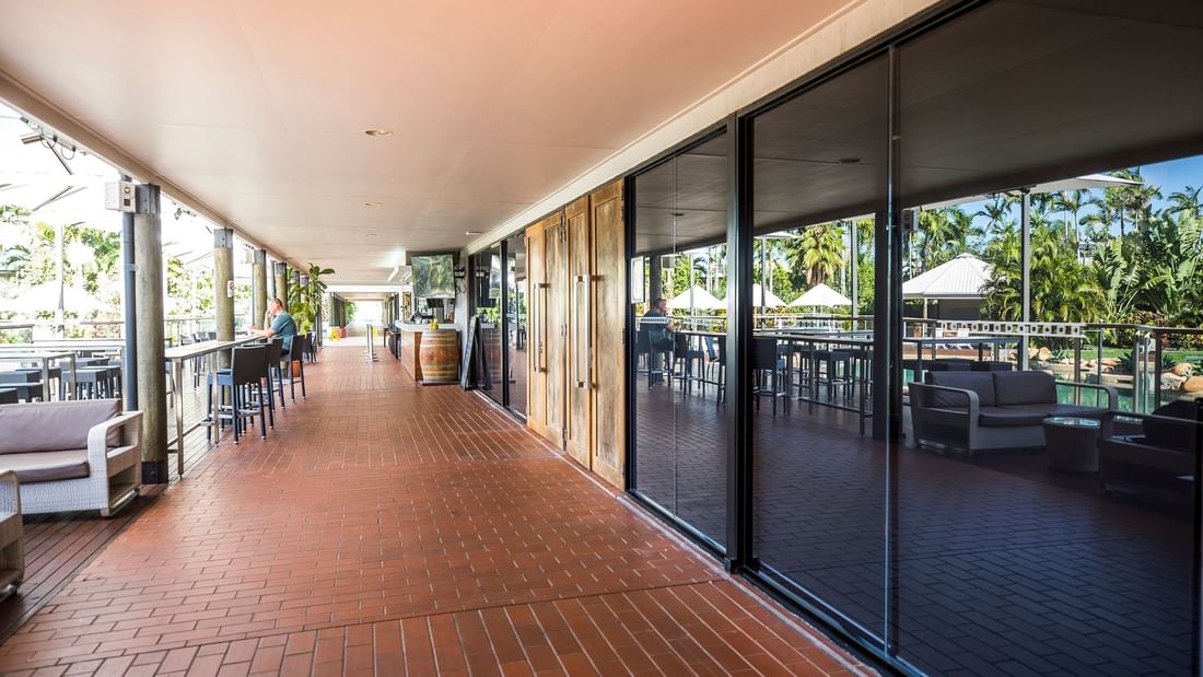 Sunlit corridor with tiled flooring, framed by modern glass panes in Lakes Room at Mercure Hotel Townsville