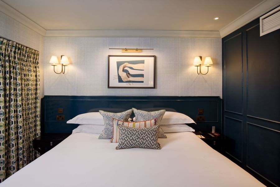 Bed with plush pillows under wall lamps in Hyde Park Suite at The Capital Hotel, Apartments and Townhouse