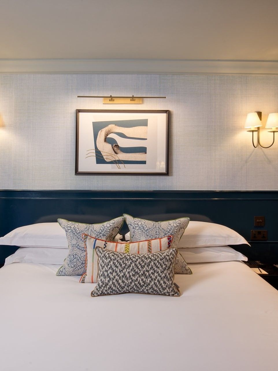 Bed with plush pillows under wall lamps in Hyde Park Suite at The Capital Hotel, Apartments and Townhouse