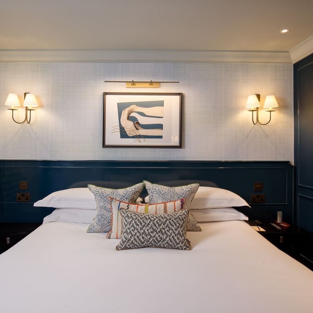 Bed with plush pillows under wall lamps in Hyde Park Suite at The Capital Hotel, Apartments and Townhouse