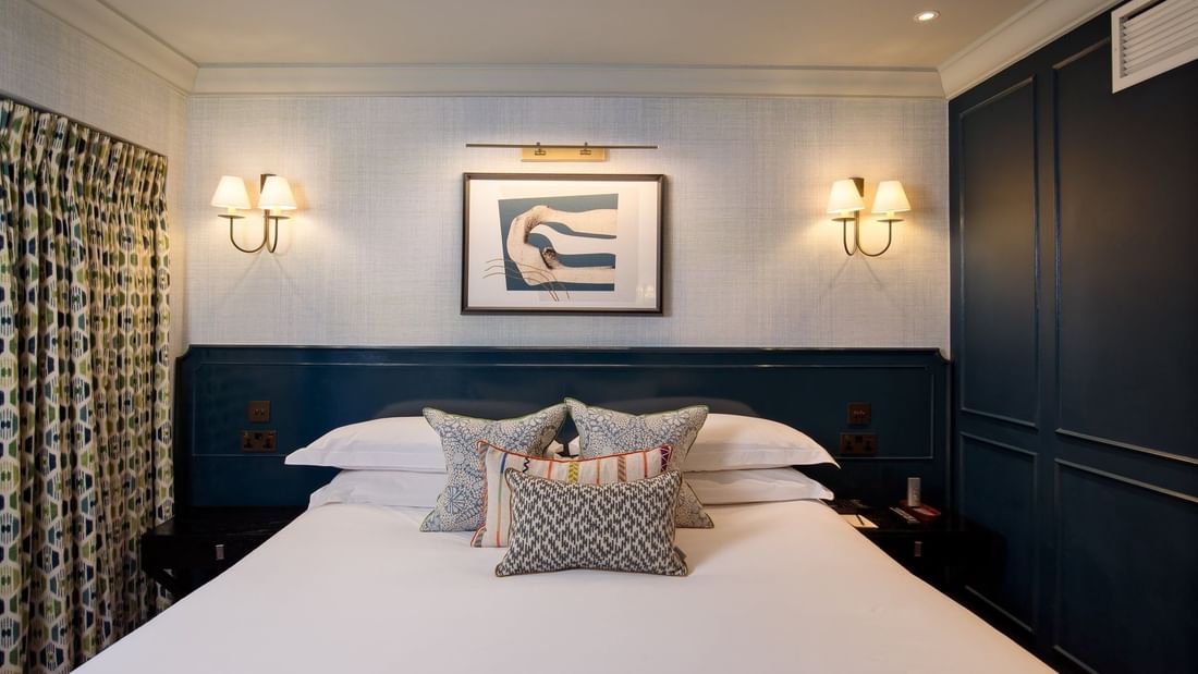 Bed with plush pillows under wall lamps in Hyde Park Suite at The Capital Hotel, Apartments and Townhouse