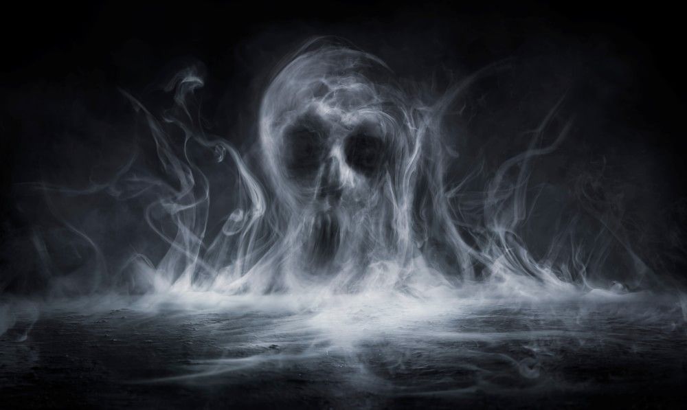 A skull made of smoke rises in the haze of a black backdrop.