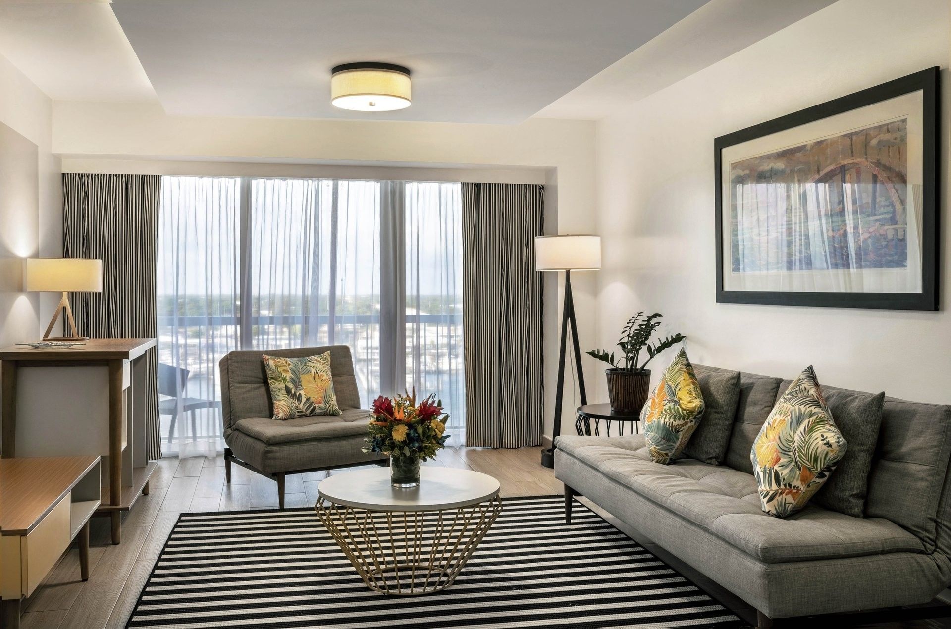 One Bedroom Harbourfront Suite with grey couch by a round table under a ceiling light at Warwick Paradise Island Bahamas