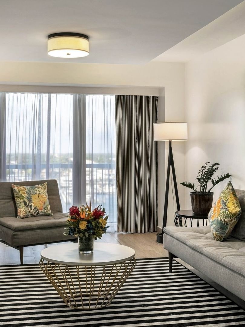 One Bedroom Harbourfront Suite with grey couch by a round table under a ceiling light at Warwick Paradise Island Bahamas