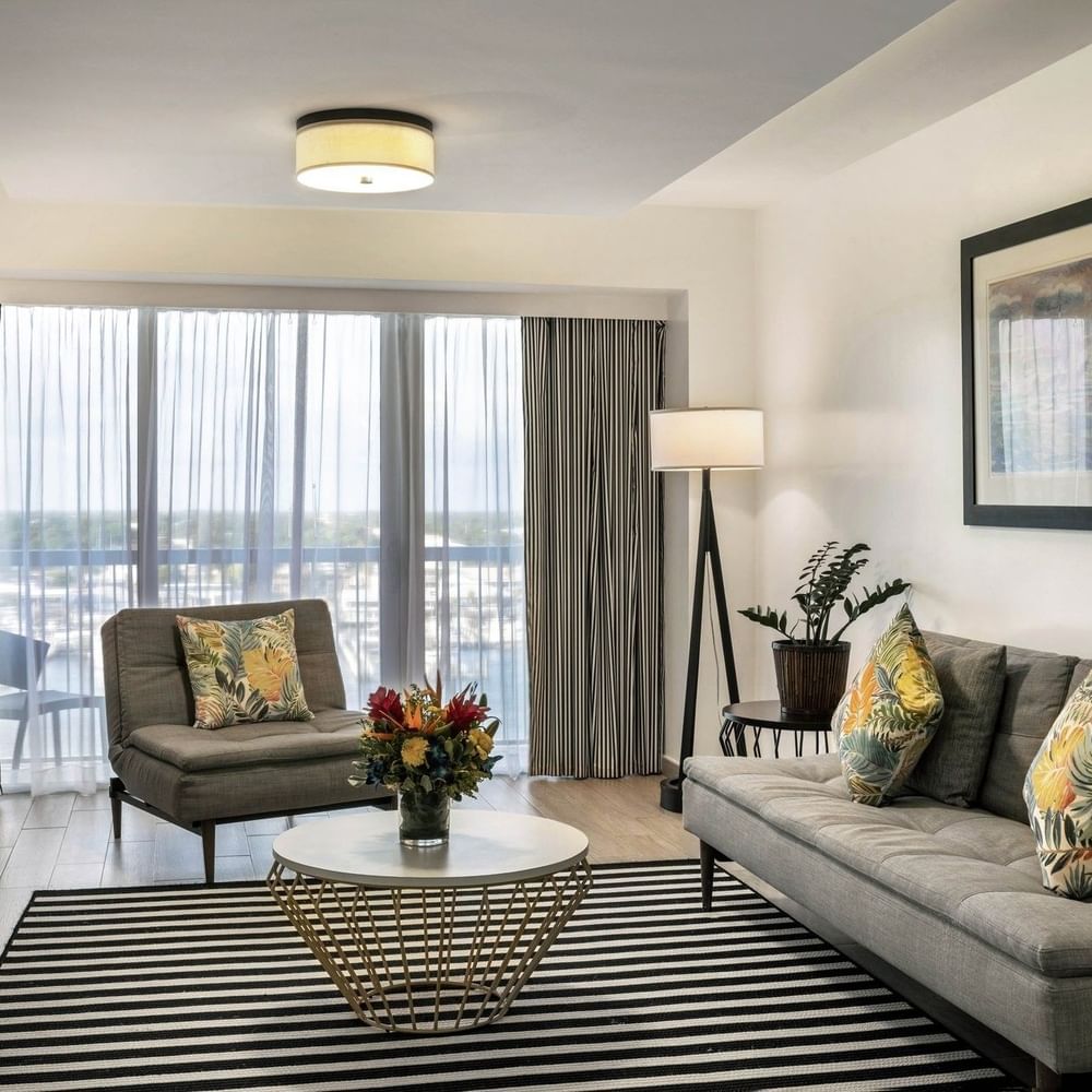 One Bedroom Harbourfront Suite with grey couch by a round table under a ceiling light at Warwick Paradise Island Bahamas