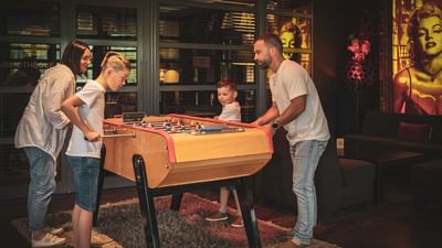 A family of four playing a game of foosball in a room with a large mural.