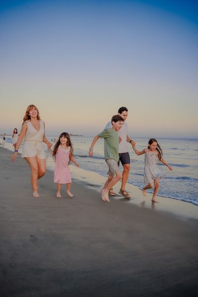 Family of five walking hand in hand along the beach at sunset at Playa Blanca Beach Resort