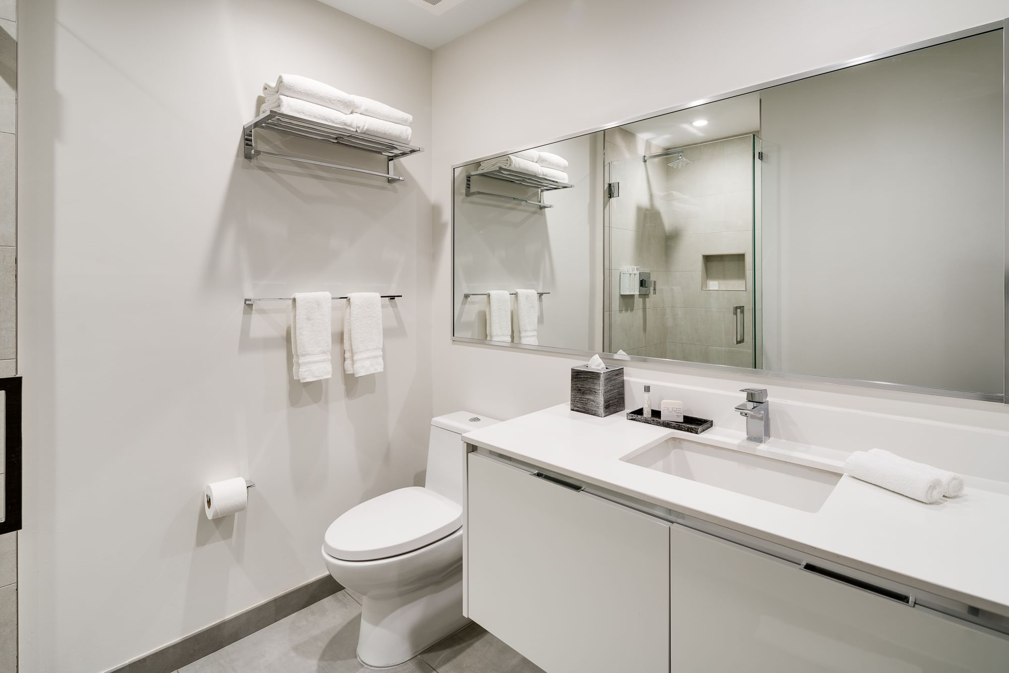 A clean and modern bathroom with a toilet, sink, and mirror.
