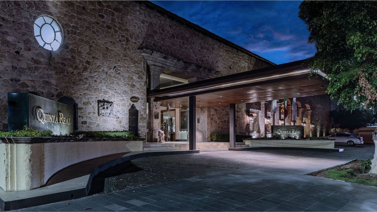 Stone facade entrance with a modern canopy and warm lighting at Quinta Real Guadalajara