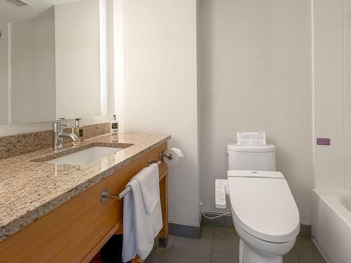 Hotel bathroom with toilet, sink, and bathtub at Coast Chilliwack Hotel by APA.