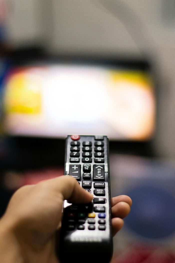 Close-up of a person clicking on the remote at Anaheim Portofino Inn & Suites